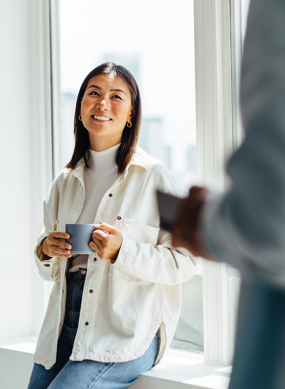 Woman holding a mug next to an office window